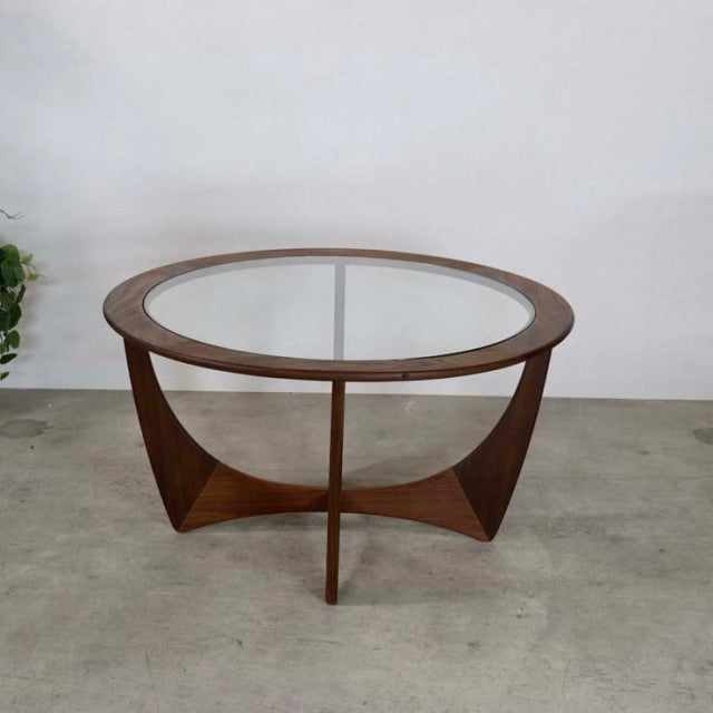 Vintage teak G-PLAN mid-century British coffee table with round glass top and sculpted wooden legs.