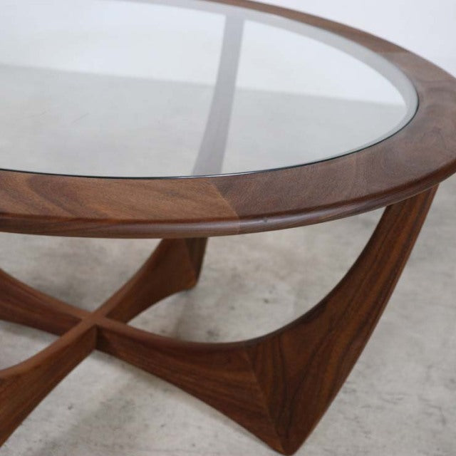 Vintage British mid-century teak coffee table by G-PLAN with round glass top and sculpted wooden legs showing rich wood.