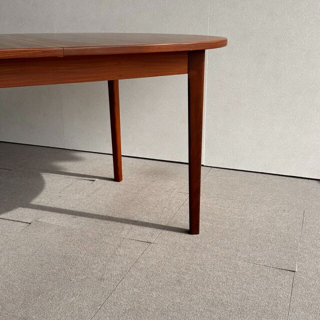 Mid-century British vintage teak oval dining table with tapered legs and smooth wood grain finish.