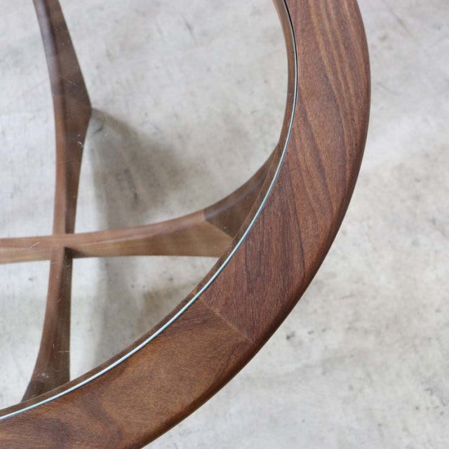 Vintage teak G-PLAN mid-century coffee table with round glass top, smooth wood grain, and crossed wooden legs in British.