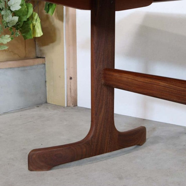 Close-up of teak wood leg and base of vintage British G-Plan mid-century dining table showcasing rich wood grain and smooth.