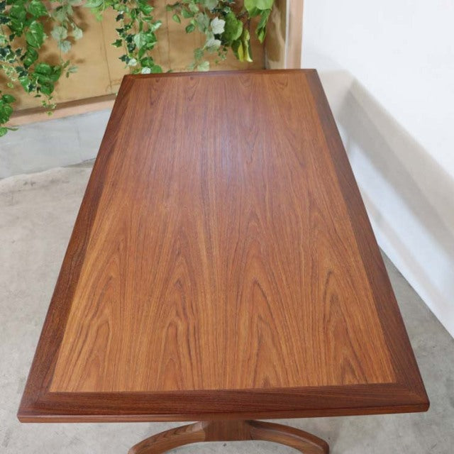 Mid-century British vintage teak dining table with rich wood grain and rounded edges, rectangular form.