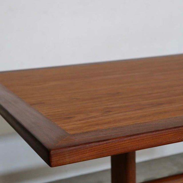 Mid-century British vintage teak dining table with rectangular top and rounded edges, visible wood grain, and sturdy.