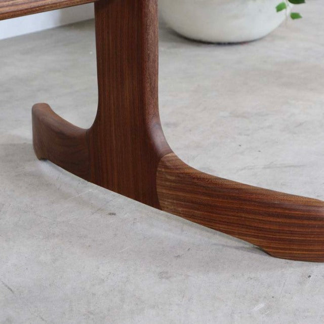 Close-up of vintage teak G-Plan British mid-century dining table leg showcasing smooth wood grain and curved craftsmanship.
