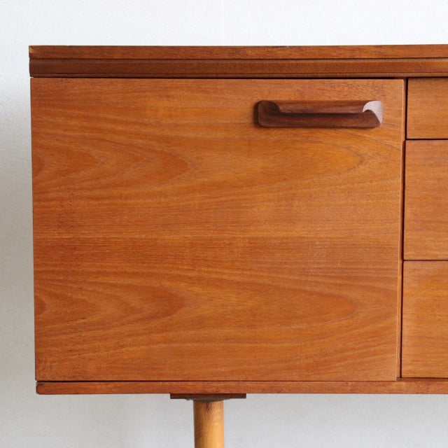 Mid-century British teak sideboard by William Laurence with warm wood grain, minimalist handle, and tapered legs.