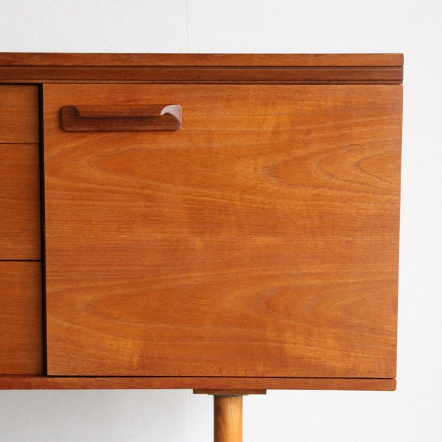 Mid-century British teak sideboard by William Laurence with smooth wood grain and clean lines, tapered legs.