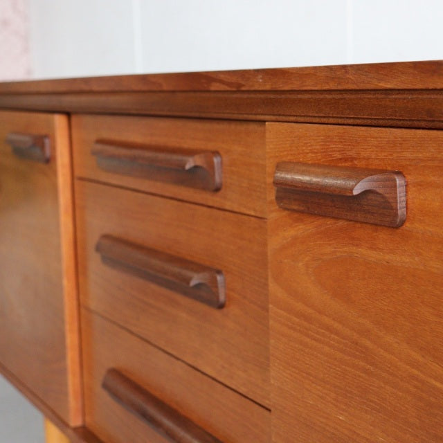 Mid-century vintage British teak sideboard by William Laurence with rich wood grain and sculpted wooden handles.