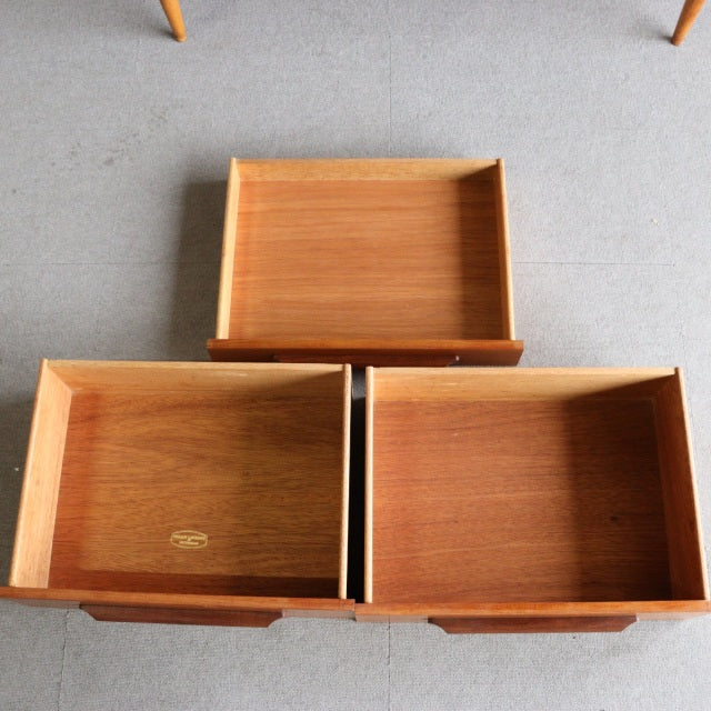 Three vintage teak drawers from a mid-century British William Laurence sideboard, showing smooth wood grain and clean edges.