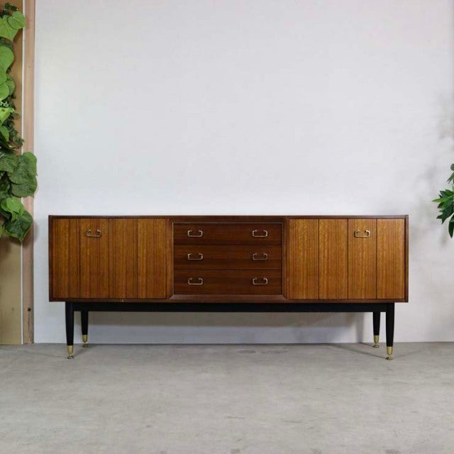 Mid-century vintage teak G-PLAN Goldstamp sideboard with rich wood grain, brass handles, and slender black legs from.