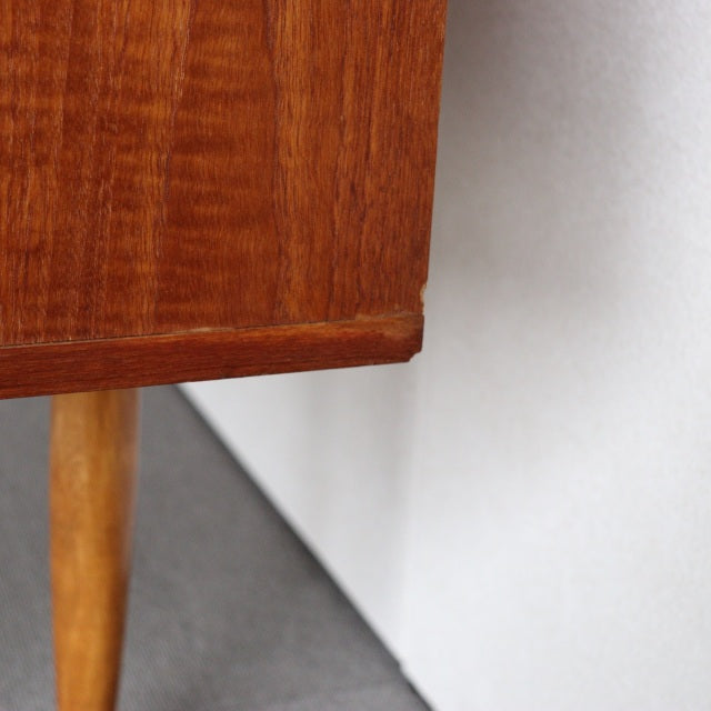 Close-up of vintage teak sideboard corner showcasing smooth wood grain, tapered British mid-century legs, and craftsmanship.