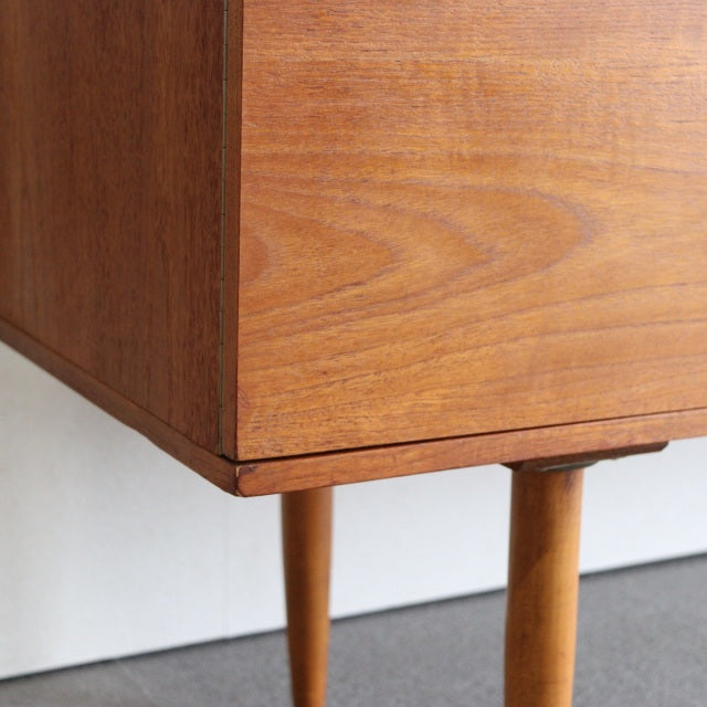 Close-up of vintage teak British mid-century sideboard corner showcasing fine wood grain and tapered legs from Denmark.