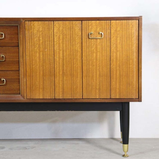 Mid-century British G-PLAN teak sideboard with vertical grain doors, black tapered legs, and brass feet accents.