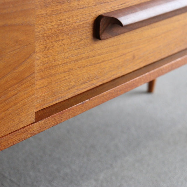 Close-up of vintage teak sideboard by William Laurence, highlighting rich wood grain, smooth curved handle, and mid-century.