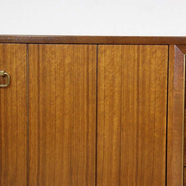 Close-up of vintage teak G-PLAN Goldstamp sideboard door panels showing vertical wood grain and brass handle, mid-century.
