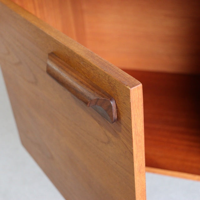Vintage teak mid-century William Laurence British sideboard door with sculpted handle and visible wood grain.