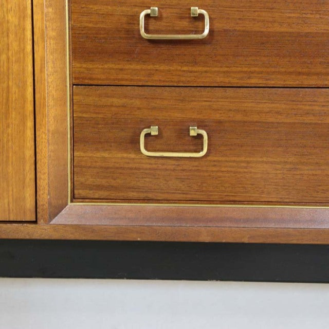 Close-up of vintage British mid-century G-Plan Goldstamp teak sideboard drawer with brass handles and detailed wood grain.