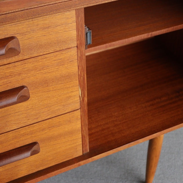 Mid-century British teak sideboard by William Laurence with smooth wood grain, tapered legs, and recessed drawer handles.
