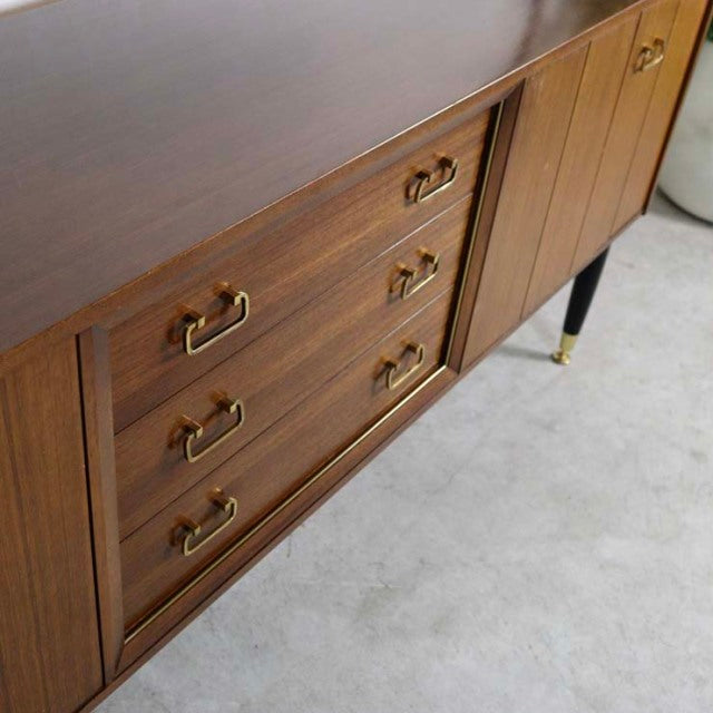 Mid-century British G-PLAN teak sideboard with gold stamped handles, three drawers, wood grain detail, tapered legs with.
