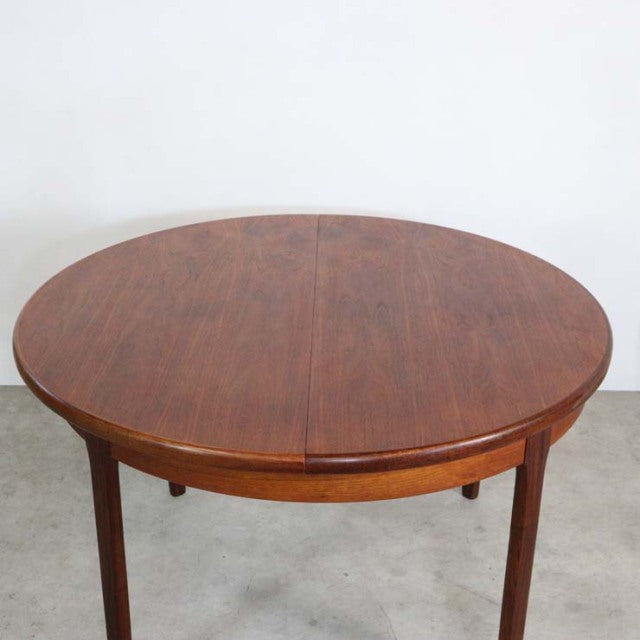 Round mid-century vintage teak dining table by Elliotts of Newbury with rich wood grain and slender tapered legs.