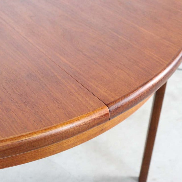 Close-up of a vintage British mid-century teak dining table corner showing smooth wood grain and rounded edge with tapered.