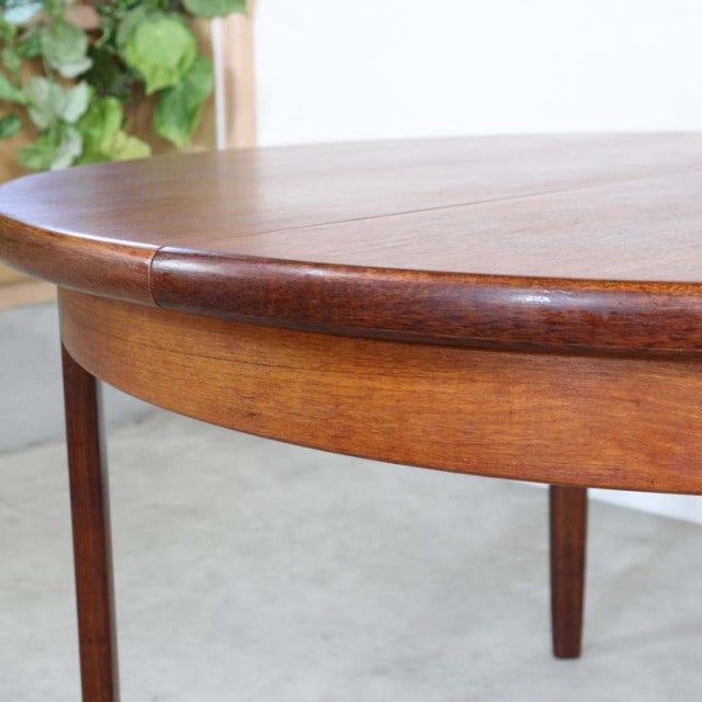 Vintage teak oval dining table with smooth wood grain, rounded edges, slender tapered legs, British mid-century design by.
