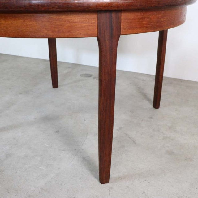Mid-century British vintage teak dining table with rounded edge and tapered legs showing rich wood grain.