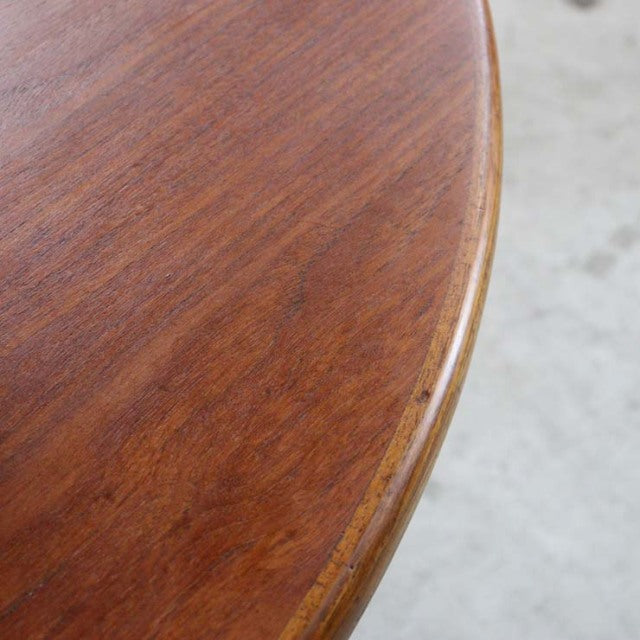 Close-up of vintage British mid-century teak dining table edge showing smooth wood grain and rounded contour.