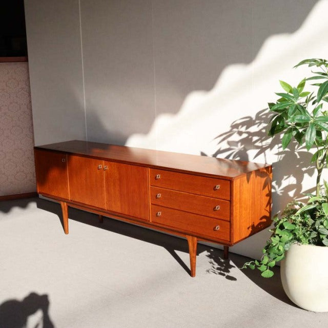Vintage mid-century teak sideboard by Younger, British-Denmark design with smooth wood grain, tapered legs, and mixed door.