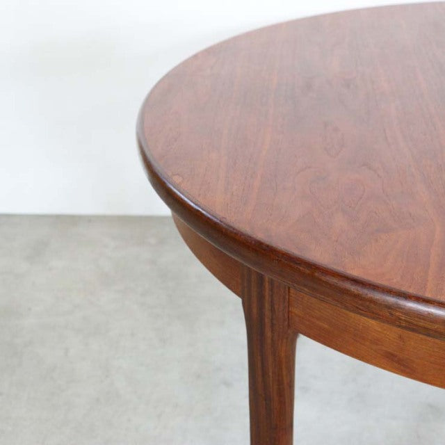 Round vintage teak dining table with smooth grain top and tapered British mid-century legs.