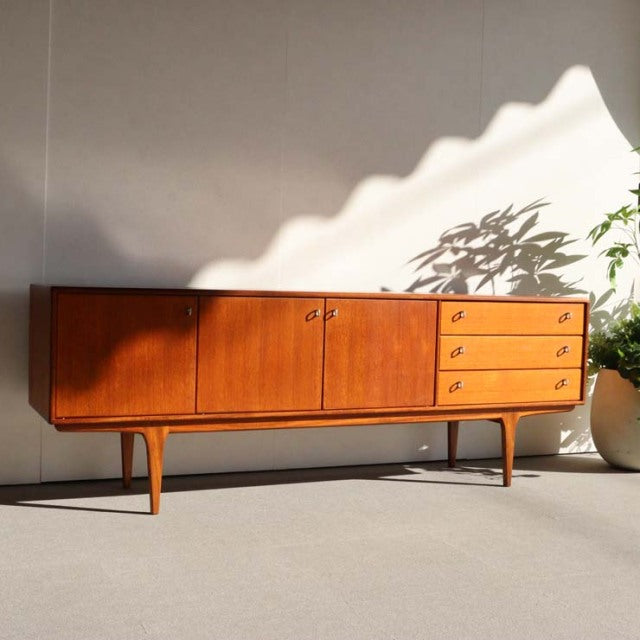 Vintage teak sideboard by Younger with mid-century British-Denmark design, featuring smooth wood grain, tapered legs, two.