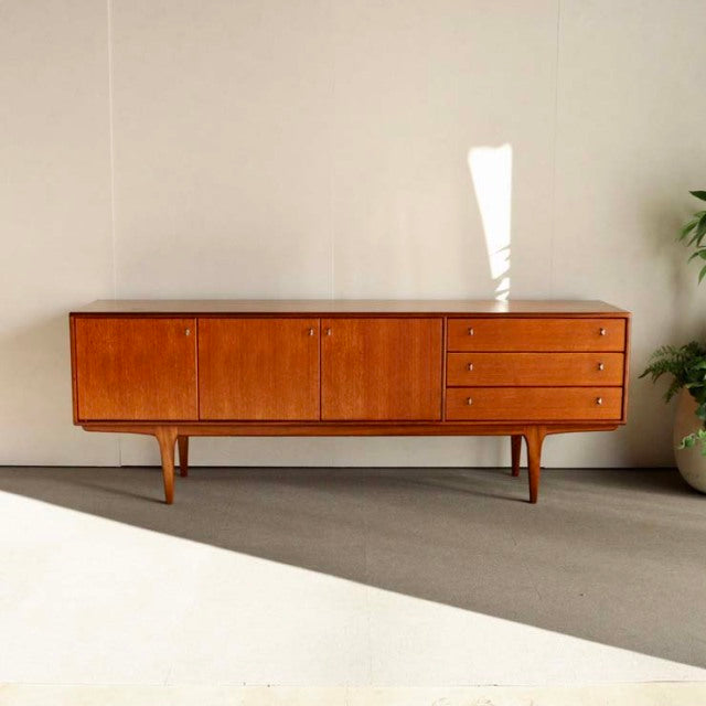 Vintage teak sideboard from Younger, British mid-century design with clean wood grain, tapered legs, and three drawers.