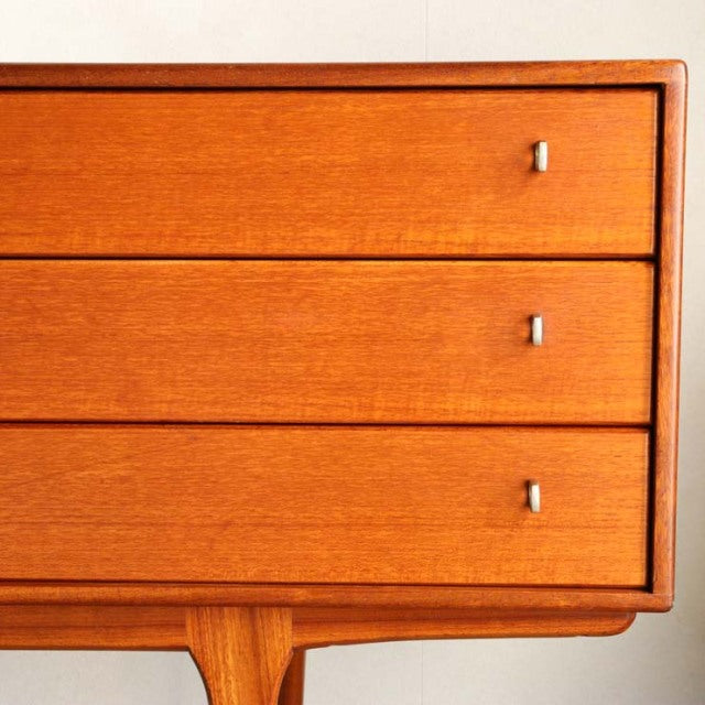 Vintage teak British mid-century sideboard drawers with sleek silver handles and warm wood grain detailing.