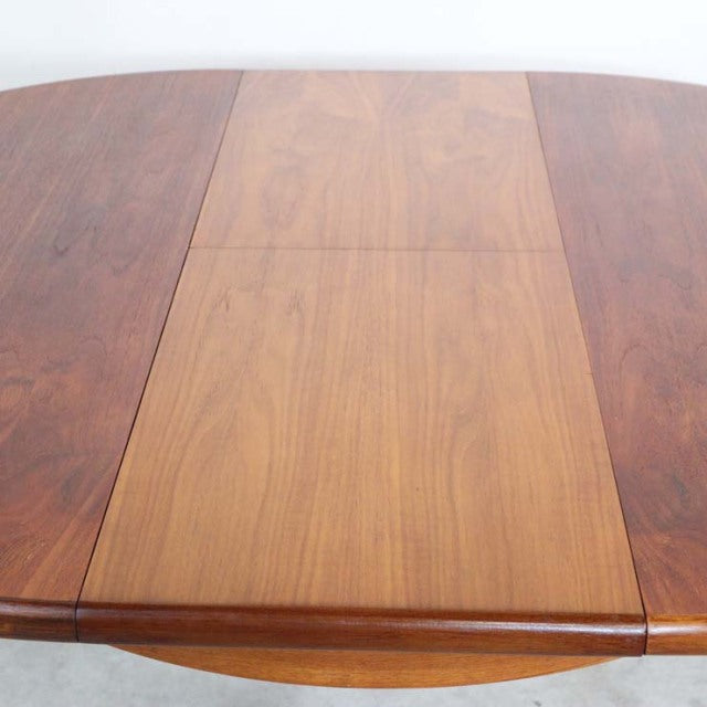 Vintage British mid-century teak dining table with oval top, smooth wood grain, and rounded edges.