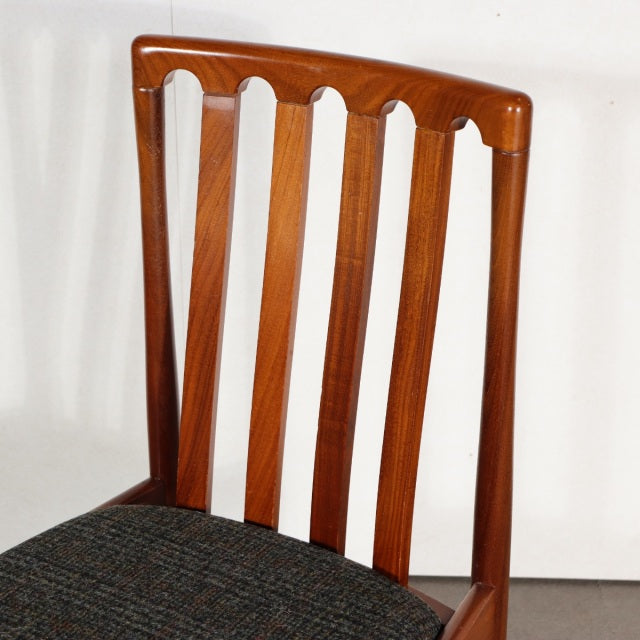 Vintage mid-century teak dining chair with vertical slatted British design and dark fabric seat, sleek legs.