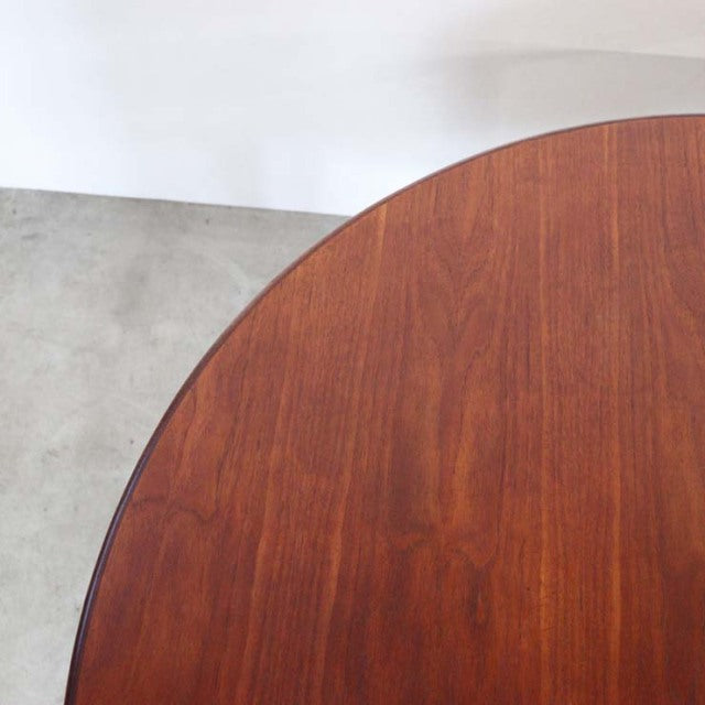 Round mid-century teak dining table by Elliotts of Newbury with rich wood grain and slender tapered legs.