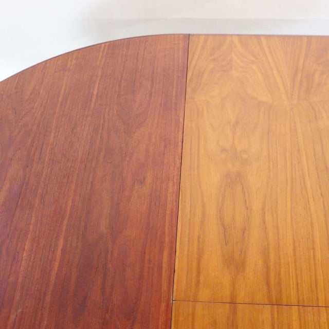 Mid-century British vintage teak dining table with oval top showing warm wood grain and smooth finish.