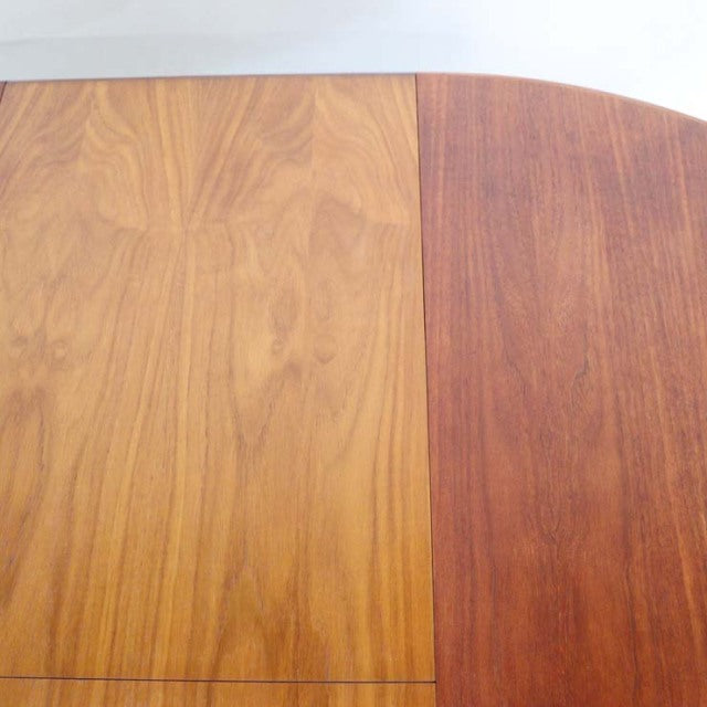 Vintage British mid-century teak dining table with smooth oval top showcasing rich wood grain patterns.