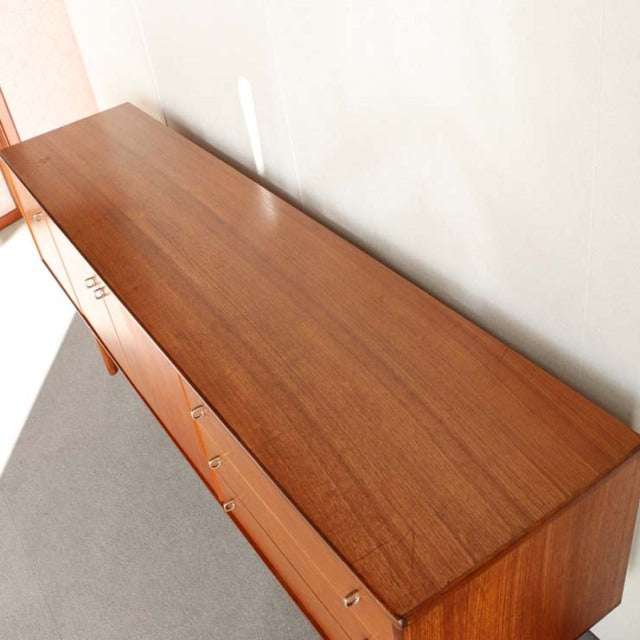Vintage mid-century teak sideboard by Younger with smooth wood grain, clean lines, and slender tapered legs reflecting.