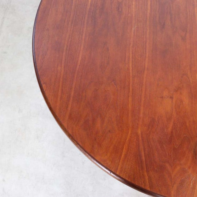 Round vintage British teak dining table with smooth grain and mid-century Danish style legs.