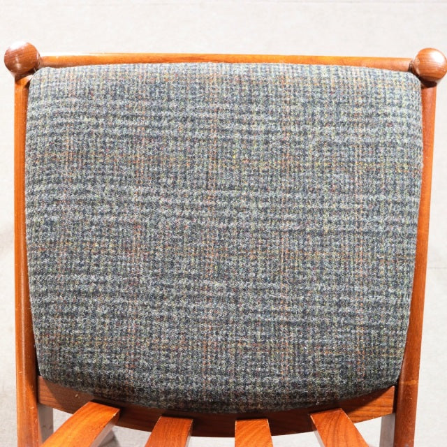 Vintage mid-century British teak dining chair backrest with textured blue-gray fabric upholstery and rounded teak frame.