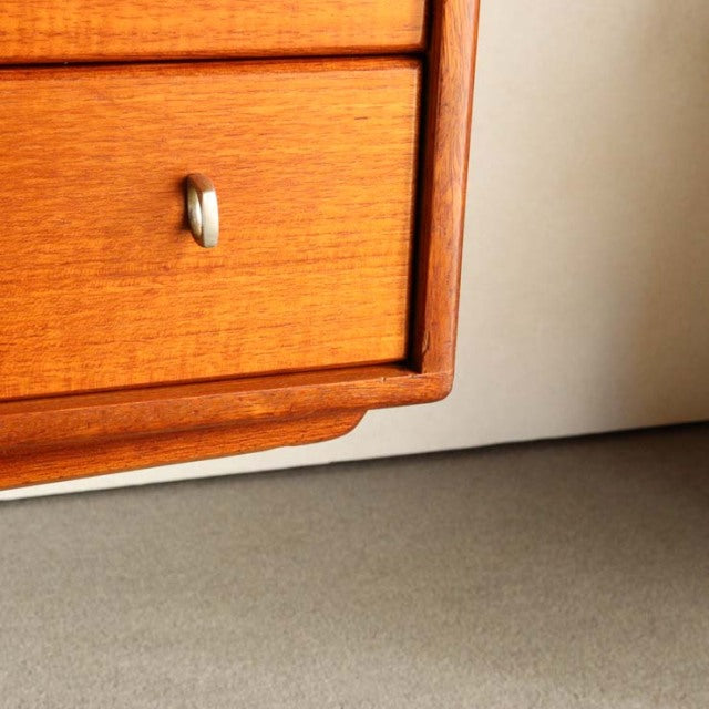 Close-up of vintage teak Youngers mid-century sideboard corner with smooth wood grain and silver knob, British-Denmark style.