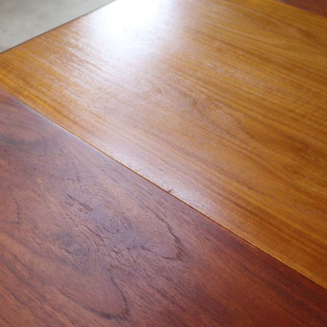 Vintage teak dining table surface showcasing smooth mid-century British craftsmanship with rich wood grain and warm tones.