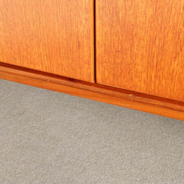 Mid-century British teak sideboard with rich wood grain and sleek, minimalist base detail.