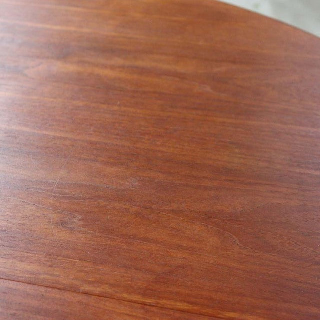 Close-up of vintage mid-century British teak dining table top showing rich wood grain and smooth finish.