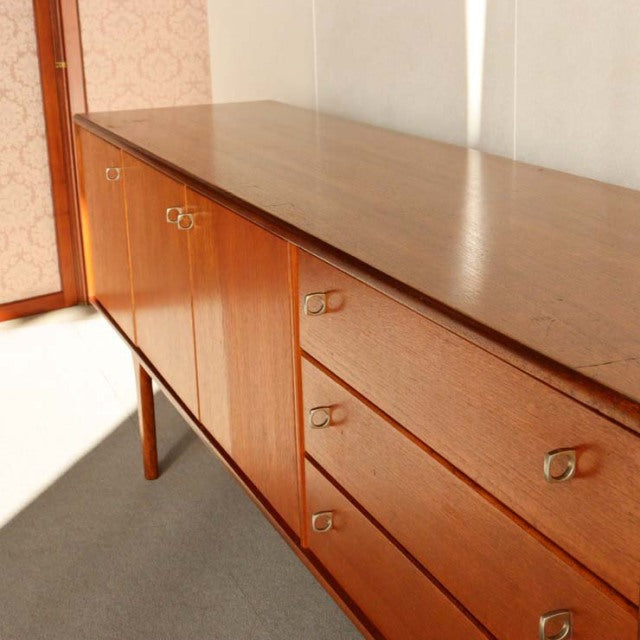 Vintage teak sideboard by Younger featuring mid-century British design with clean lines, brass ring handles, and tapered.