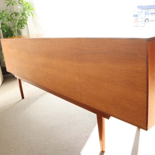 Mid-century British teak sideboard by Younger with clean wood grain and slender tapered legs in bright natural light.