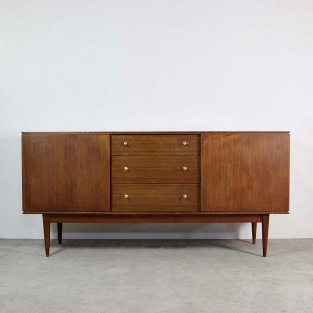 Mid-century British vintage teak sideboard with rich wood grain, three central drawers, and tapered legs.
