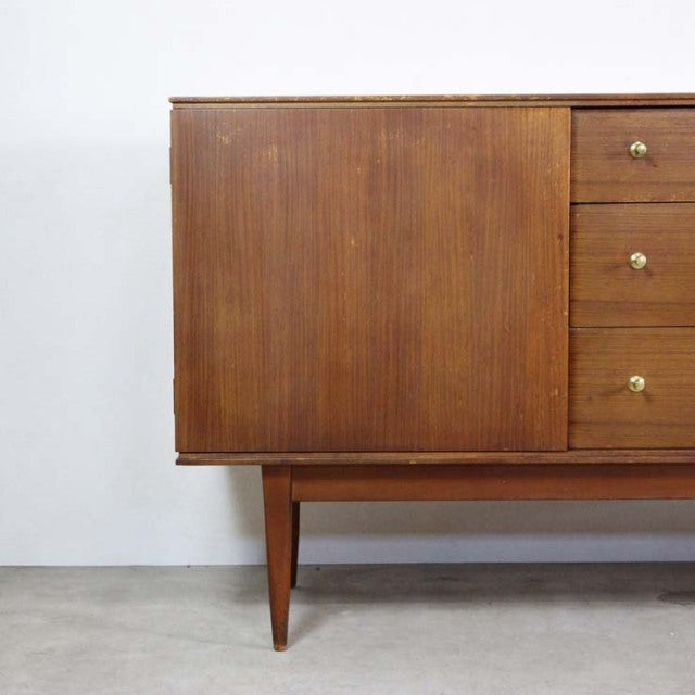 Mid-century British vintage teak sideboard with rich wood grain, tapered legs, and brass drawer knobs, showcasing classic.