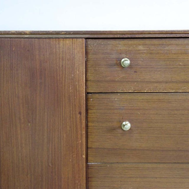 Vintage British teak sideboard with mid-century design, smooth wood grain, and brass knobs on drawers.