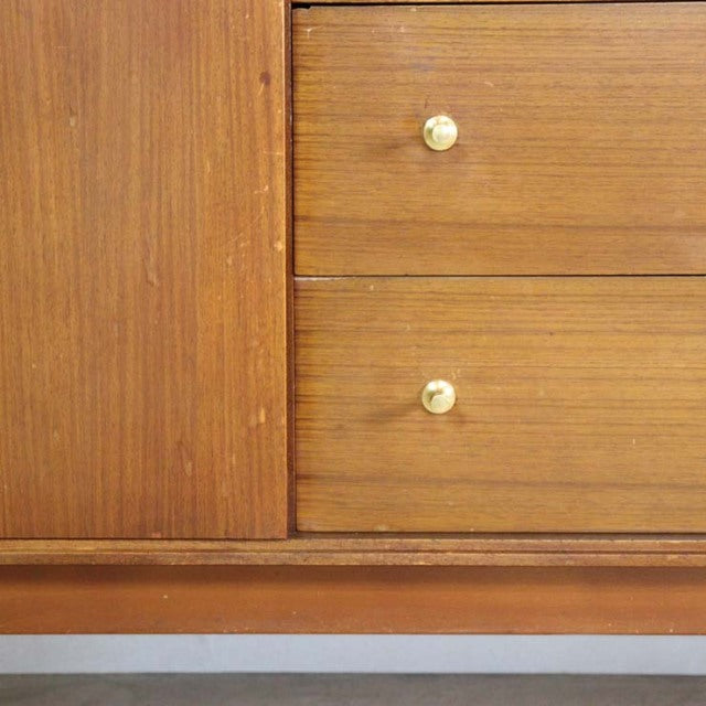 Vintage British mid-century teak sideboard with rich wood grain, brass knobs, and sleek Danish-style legs.